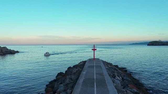 Scenic, real-time shot of colorful traditional fishing boats moored in the small, quaint port of Cand&aacute;s, Asturias, Spain. Historic coastal town architecture surrounds the harbor on a cloudy day