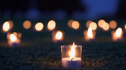 Candlelight vigil at dusk. Flickering candles illuminate grass, creating warm atmosphere. Peaceful gathering reflects hope and remembrance. - Powered by Adobe