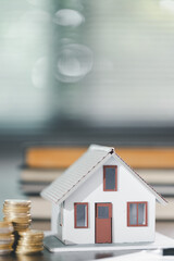 House model placed beside money coins illustrates concept of saving and financial planning for buying home, highlighting investment, mortgage options, home loans, refinancing, smart finance strategies