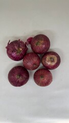 Raw red onions, a staple kitchen ingredient, with one onion neatly halved to display its beautiful cross-section. This image is excellent for food preparation, seasoning, gourmet cooking, and vegetabl