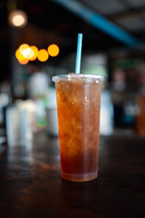 Lemon iced tea in a tall glass with crushed ice on wood table