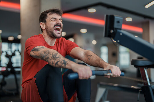 Bright Indoor Gym Scene Man Exercising On Rowing Machine Showing Intense Focus And Effort