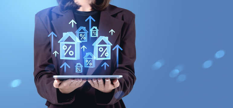 Businesswoman holding tablet with floating house icons and percentage signs representing rising real estate mortgage rates and housing market trends concept.