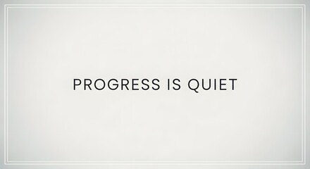 Obraz premium A minimalist white wall with the phrase 'Progress is Quiet' written in simple black text, emphasizing subtlety and understated achievement