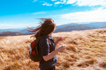 A young girl with flying in the wind hair enjoys a walk in the autumn mountains