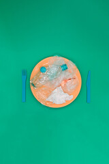 Plastic and organic garbage on the plate, concept of bad and unhealthy food