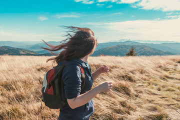 Young girl with flying in the wind hair enjoys the hiking, nature and autumn mountains