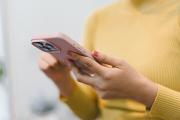 Focused woman in yellow sweater using her hand for communication, typing on smartphone. Browsing online with modern mobile technology