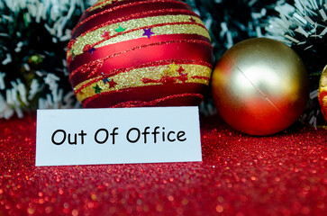 Out of Office text on white banner notepad with Christmas decoration background.
