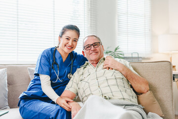 Obraz premium Young nurse caregiver smiling with elderly man on living room sofa showing warmth and support