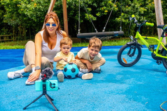 Influencer mom recording video with children at playground
