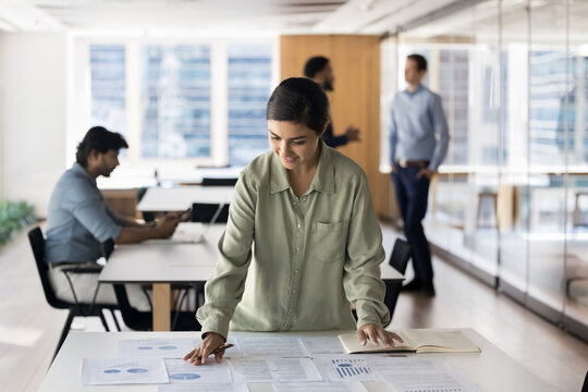 Young Indian woman financial analyst manage statistical report at office