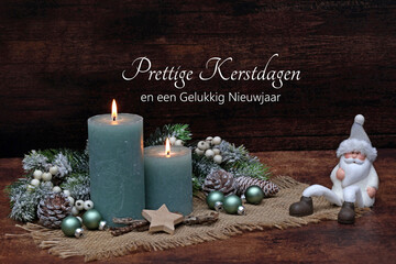 Christmas card Vrolijk Kerstfeest: Christmas decoration with candle, fir branches and Christmas ornaments with the text Merry Christmas and a Happy New Year in Dutch.
