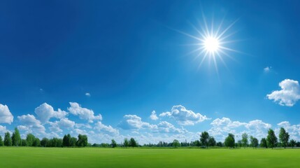 Obraz premium Bright Blue Sky Over Green Field with Fluffy White Clouds and Glorious Sun Shining in the Clear Skies Creating a Peaceful Landscape Scene