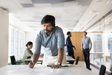 Concentrated male project manager work with statistics in paper documents