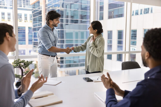 Male leader handshaking with millennial female worker before applauding teammates - Powered by Adobe
