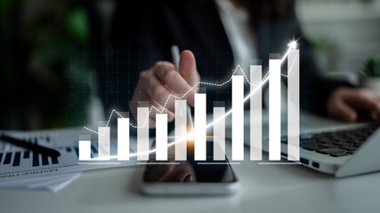 A business professional analyzes financial data through graphs and charts while using a smartphone...