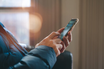 hands using smartphone indoors, browsing or texting with blurred background and warm light. Great for lifestyle, communication, technology, mobile app digital connection content.