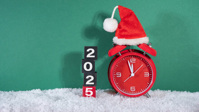 Merry Christmas, year 2025 or saint nicholas day, celebration holiday greeting card  - countdown, santa hat on red retro alarm clock in snow, isolated on green background