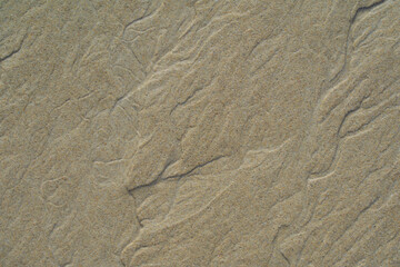 Close-up of sand patterns formed by wind and water erosion. Fine lines and textures create a fascinating natural artwork on the beach.