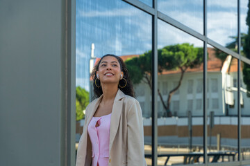 Young woman smiling, enjoying music with earbuds while walking outdoors