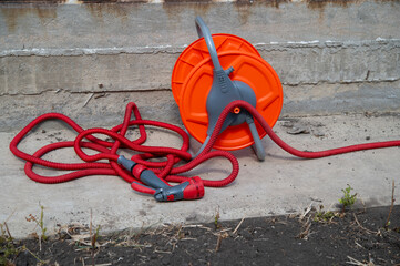 Outdoor garden tool reel with handle. Garden watering hose with nozzle for plants and household needs.
