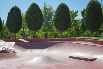 Skateboard in city. Empty public red skate park waiting for skaters. Skate and Bike Park. Extreme sports ground	