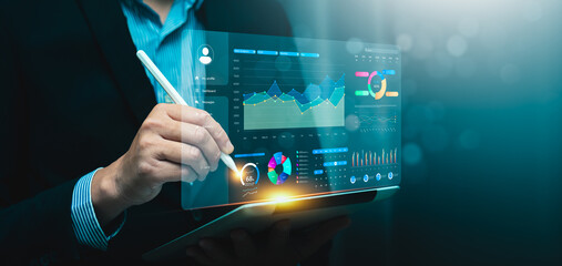 Businessman using digital tablet to analyze data with futuristic dashboard, financial charts, symbolizing innovation, big data, business intelligence, digital transformation, financial analytics
