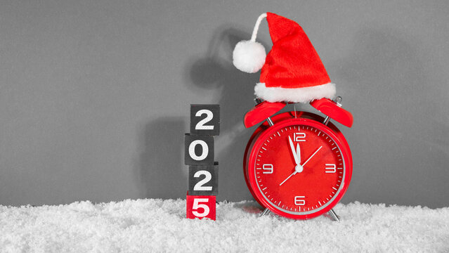 Merry Christmas, year 2025 or saint nicholas day, celebration holiday greeting card - countdown, santa hat on red retro alarm clock in snow, isolated on gray background - Powered by Adobe