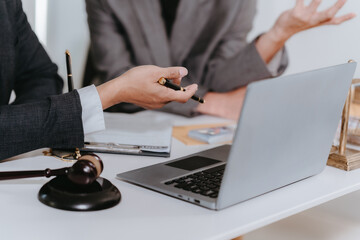 Lawyer, man giving advice to client at table with scales and gavel. Lawyer handing document and pen...