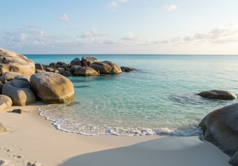 Smooth weathered boulders line the edge of turquoise tropical ocean water on a sandy shore