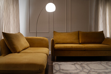 design of stylish living room with stylish yellow sofas, floor lamp next to sofa. soft muted light from lamp creates atmosphere of comfort and relaxation. sofa is close. Illuminated by lamp.