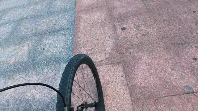 Roue de v&eacute;lo en POV qui avance sur des dalles bleues et marrons 