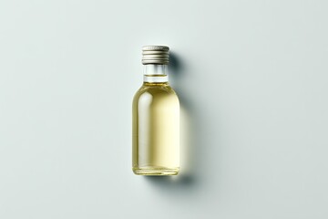 Small clear glass bottle with light gold liquid and silver cap, top view