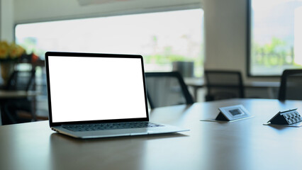 Laptop computer on meeting table with empty screen.