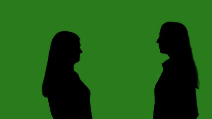 Black silhouettes of two women looking at each other against a green chroma key background. Minimalist contrast and modern visual composition, mockup.