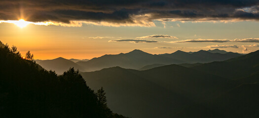 Sunset in the mountains. Summer landscape. Silhouettes of mountain peaks at sunset. Rosa Khutor mountain resort, Sochi