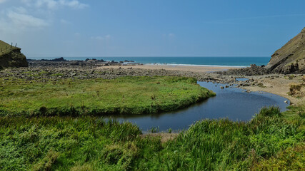 Obraz premium Stream and Shoreline: Coastal Confluence near Bude