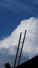 A metal ladder ascends steeply from the dark foreground silhouette, serving as a powerful visual metaphor for aspiration, reaching for dreams, and infinite vertical space.