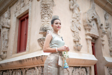 Beautiful young Asian woman in traditional Thai Dusit dress in an old temple in Chiang Mai, Thailand.