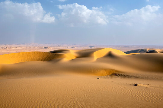 Doha, Qatar - A vast desert landscape with golden sand dunes stretching to the horizon, soft wind-blown textures on the sand, Inland Sea Qatar