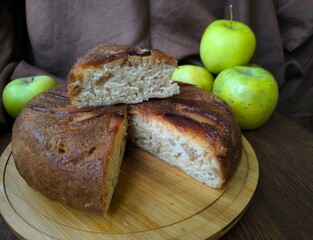 Homemade apple pie, a piece of apple pie and green apples on a dark wood background