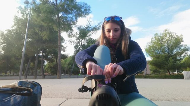 Young woman putting on inline skates outdoors