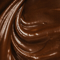 Close-up of smooth melted chocolate texture with glossy swirls, rich brown creamy surface for background or dessert concept