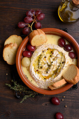 Baked brie cheese with honey, grapes, aromatic herbs and crusty bread, baked camembert	