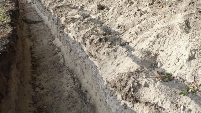 Dug trench in soil for laying utilities and construction.