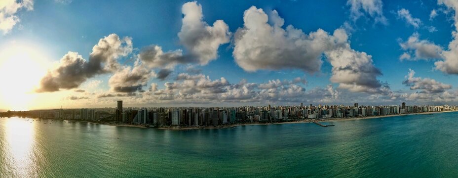 Panoramic view of city skyline along waterfront under clouds