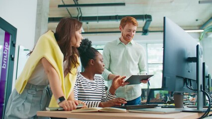 Group of coworkers standing near desk reviewing graphs on clipboard while comparing data on monitor. Team analyzing statistics and updating online reports in bright collaborative office. - Powered by Adobe
