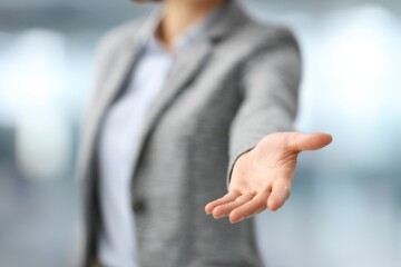A confident businesswoman extends her arm forward with an open hand, asserting control and leadership.