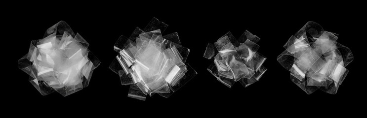 Four abstract piles of transparent adhesive tape on a black background. Clear tape pieces are crumpled and layered into sculptural shapes, showing reflections, dust, and texture.